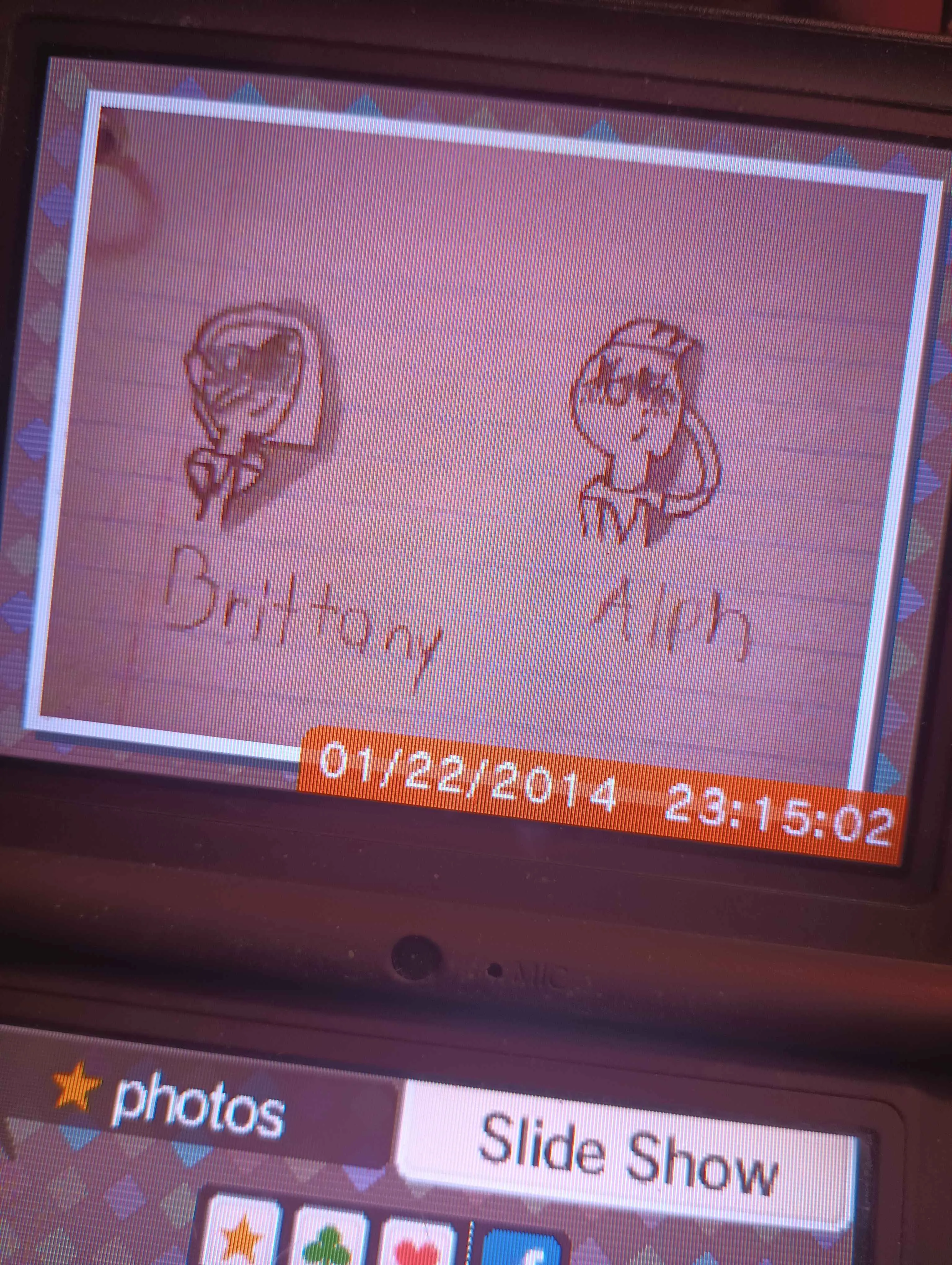 photo of a photo on a dsi. It is of old art of Alph and Brittany from Pikmin smiling nervously at eachother, heads too big for their bodies and hands hidden. It is dated 01/22/2014