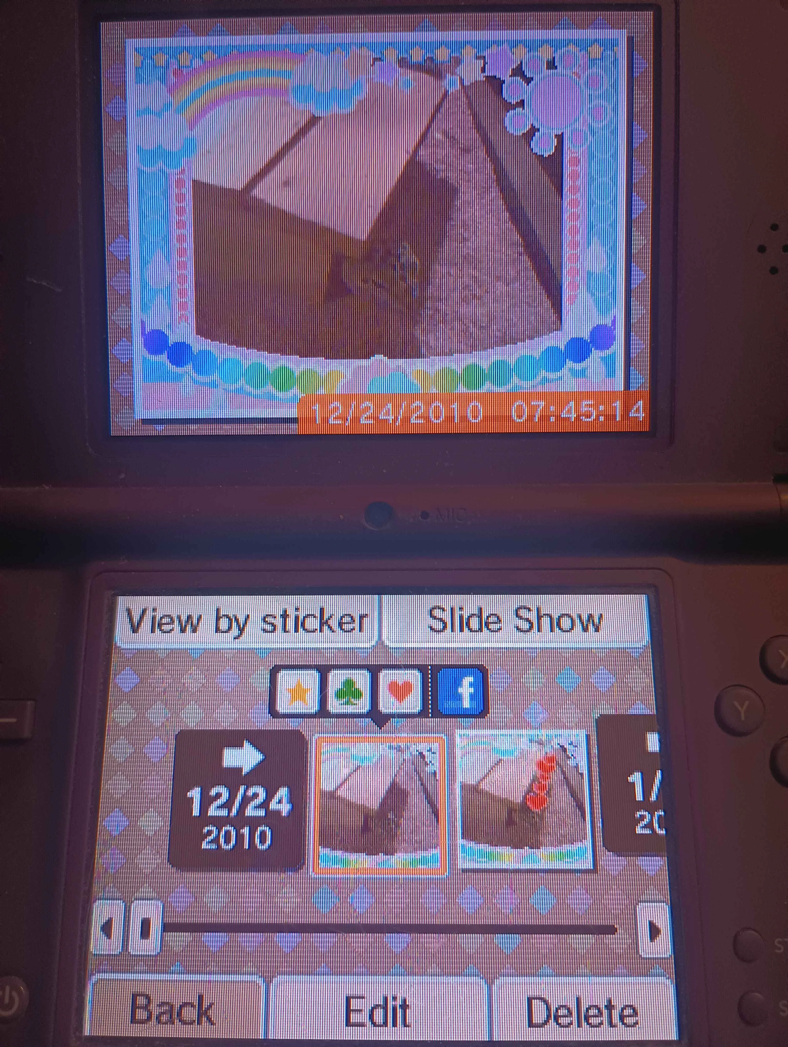 photo of a photo on a dsi. The image on the top screen is of a gecko peeking its head out from a wooden shelter inside a tank.