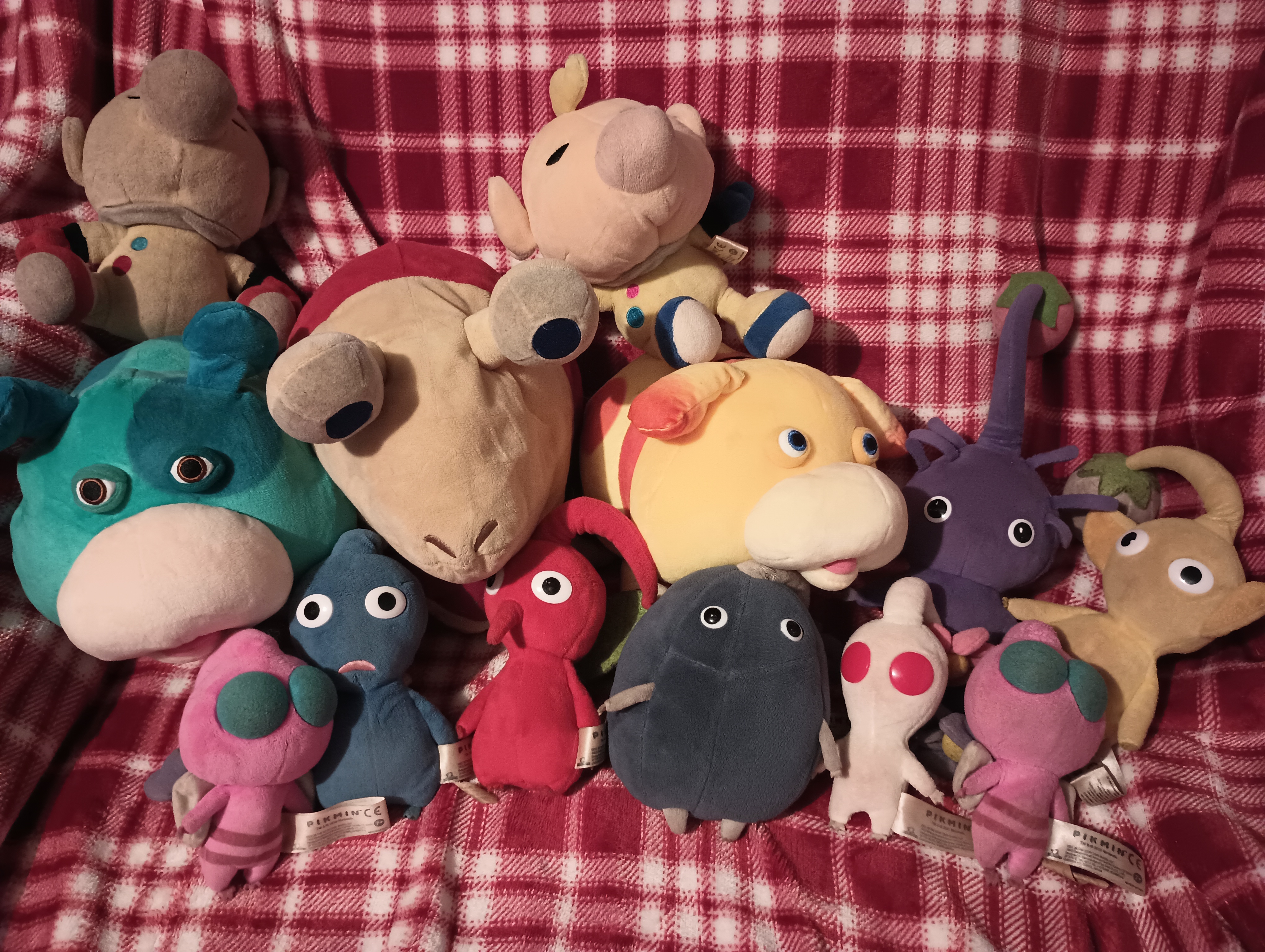 photo of most of the official pikmin plushes resting on a red blanet.